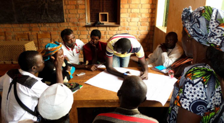 A group sitting around a table, working together in CAR while one man takes notes