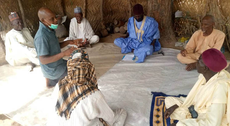 A group of people collaborating and listening to a man speak in Northeast Nigeria